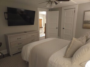 A bedroom with a bed, a dresser, a television mounted on the wall, and a ceiling fan. - Cozy renovated century home retreat minutes away from Lake Erie. (Conneaut)