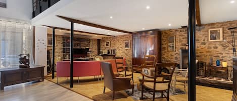 A spacious living area with a high ceiling, a dining table, and multiple chairs.