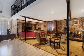 A spacious living area with a high ceiling, a dining table, and multiple chairs. - Chambre Bleue, Table d'Hôte with Terrace, Shared Garden & Wi-Fi (Fursac)