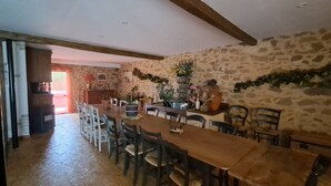 Ein Essbereich mit einem langen Holztisch, mehreren Stühlen und einer Steinwand.