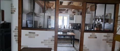 A kitchen with a wooden bench, brick wall accents, and a view through a glass partition.
