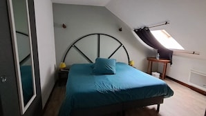 Ein Schlafzimmer mit einem Bett, zwei Nachttischen mit Lampen, einem Fenster mit Vorhang und einer Heizung.