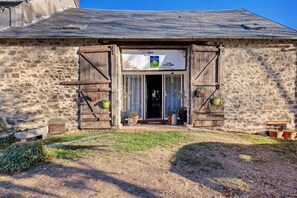A rustic stone building with a wooden door and shutters, a small porch area, and potted plants. - Red and Yellow Rooms, Table d'Hôte with Terrace, Shared Garden and Wi-Fi (Fursac)