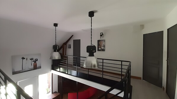 Una habitación con una escalera, una lámpara de techo y una puerta.