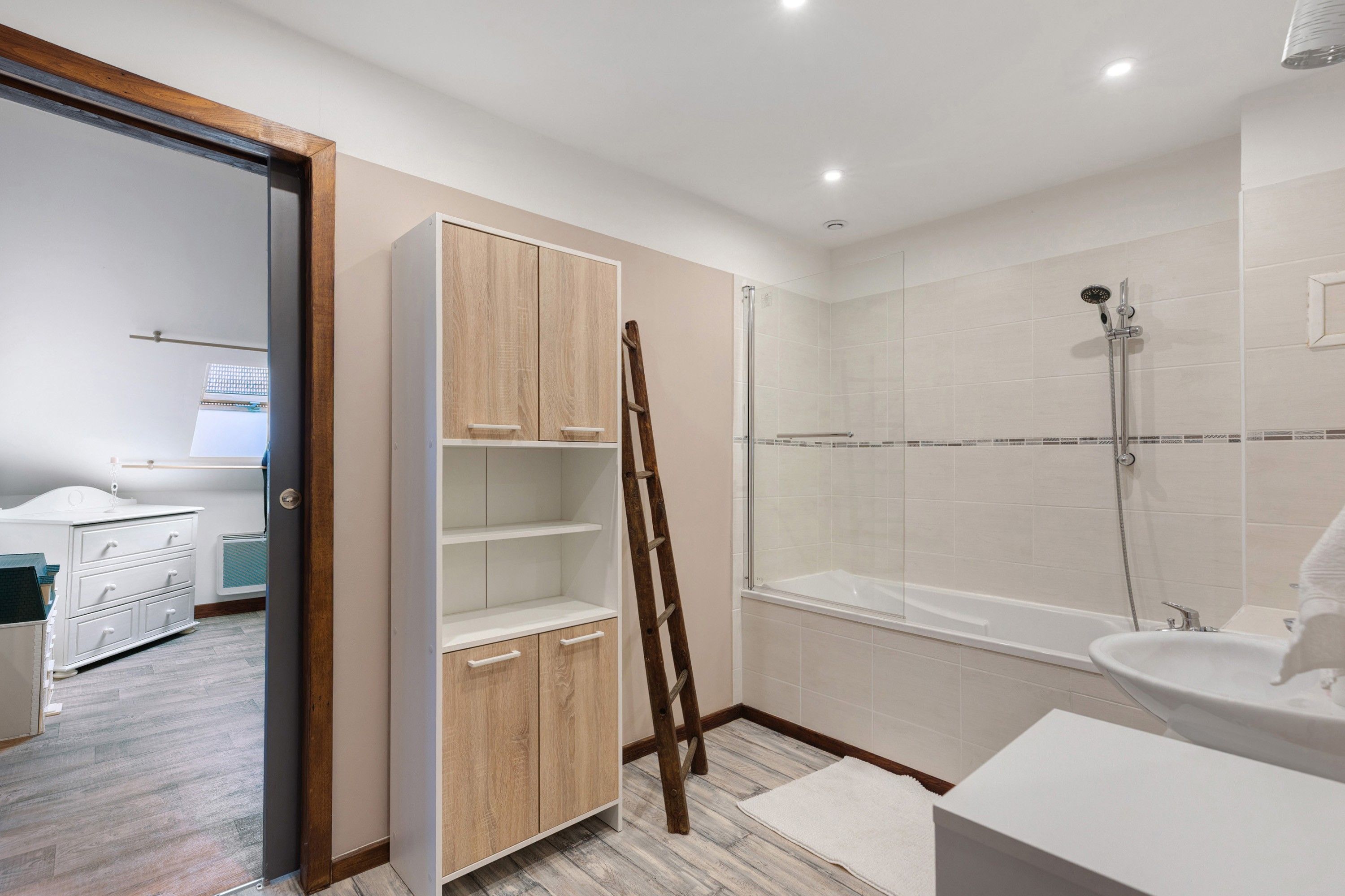 Ein modernes Badezimmer mit bodenebenen Dusche, Badewanne und weißem Waschtisch.