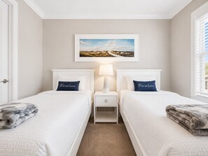 A hotel room with two beds, a nightstand with a lamp, a framed landscape picture on the wall, and a view of the outdoors through the window. - The Sandpiper Hideaway (Panama City Beach)