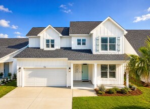 A two-story house with a garage, a front porch, and a well-maintained lawn. - The Sandpiper Hideaway (Panama City Beach)