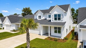 Une rangée de maisons blanches aux toits gris, une pelouse bien entretenue et un palmier.