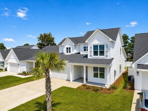 A row of white houses with grey roofs, a well-maintained lawn, and a palm tree. - The Sandpiper Hideaway (Panama City Beach)