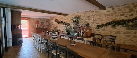 A dining area with a long wooden table, multiple chairs, and a stone wall.