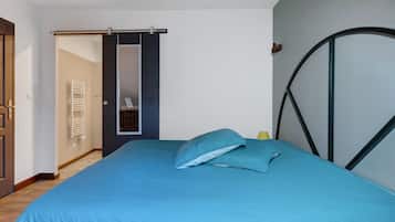 Een slaapkamer met een bed, een deur, een handdoekhouder en een spiegel aan de muur.