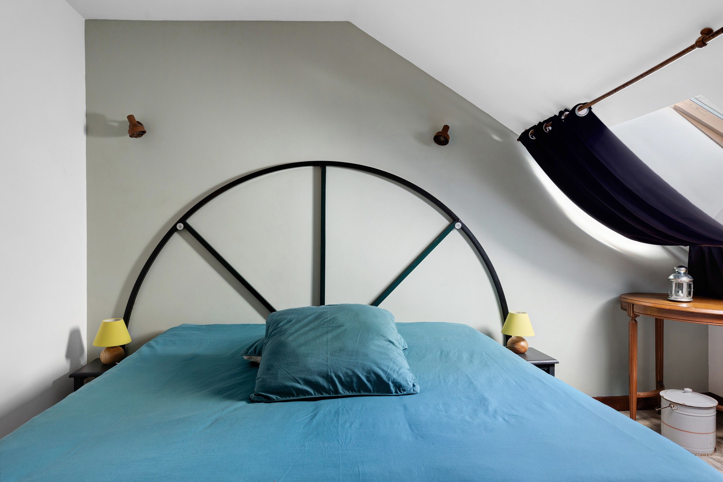 Quarto com cama, cadeira suspensa, mesa de cabeceira, abajur e um candeeiro.