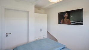 A bedroom with a bed, a wardrobe, and a television mounted on the wall. - Vacation Home at Am Ringwal 82 in Cuxhaven Duhnen—modernized in 2026 with a Wallbox (Cuxhaven)