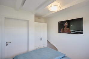 A bedroom with a bed, a wardrobe, and a television mounted on the wall. - Vacation Home at Am Ringwal 82 in Cuxhaven Duhnen—modernized in 2026 with a Wallbox (Cuxhaven)