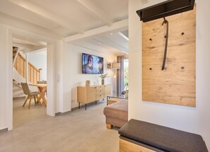 A modern interior with a staircase, dining area, and a wooden wall-mounted rack. - Vacation Home at Am Ringwal 82 in Cuxhaven Duhnen—modernized in 2026 with a Wallbox (Cuxhaven)