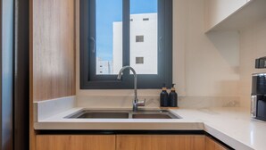 A kitchen with a double sink, wooden cabinets, a window, and a view of buildings outside. - Born | Family Getaway with Pool View (Bavaro)
