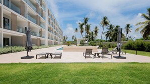 A hotel with a pool, outdoor seating, and palm trees. - Born | Family Getaway with Pool View (Bavaro)