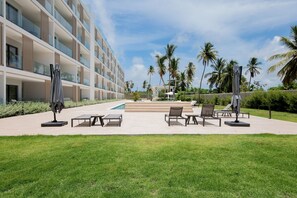 A hotel with a pool, outdoor seating, and palm trees. - Born | Family Getaway with Pool View (Bavaro)