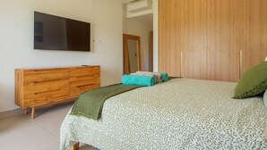 A bedroom with a bed, a wooden dresser, a television, and a wardrobe. - Born | Family Getaway with Pool View (Bavaro)