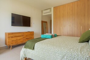 A bedroom with a bed, a wooden dresser, a television, and a wardrobe. - Born | Family Getaway with Pool View (Bavaro)