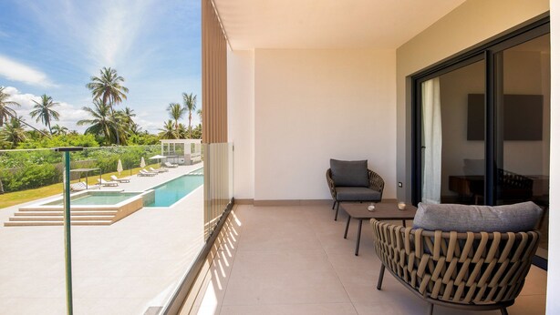 A balcony with a pool, chairs, and a table. - Born | Family Getaway with Pool View (Bavaro)