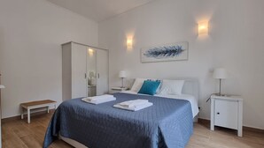 Quarto de hotel com cama, mesas de cabeceira, guarda-roupa e um quadro na parede.
