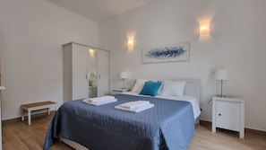 Ein Hotelzimmer mit Bett, Nachttischen, einem Kleiderschrank und einem Bild an der Wand.