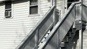 Una casa a due piani con una scala in legno e un portico.