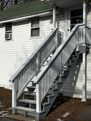 Una casa de dos pisos con una escalera de madera y un porche.