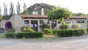 Un edificio con fachada de ladrillo, una puerta y una ventana. Hay un árbol frente al edificio.