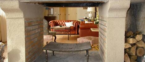 A stone fireplace with a bench in front, a red leather sofa, and a small table with a lamp.