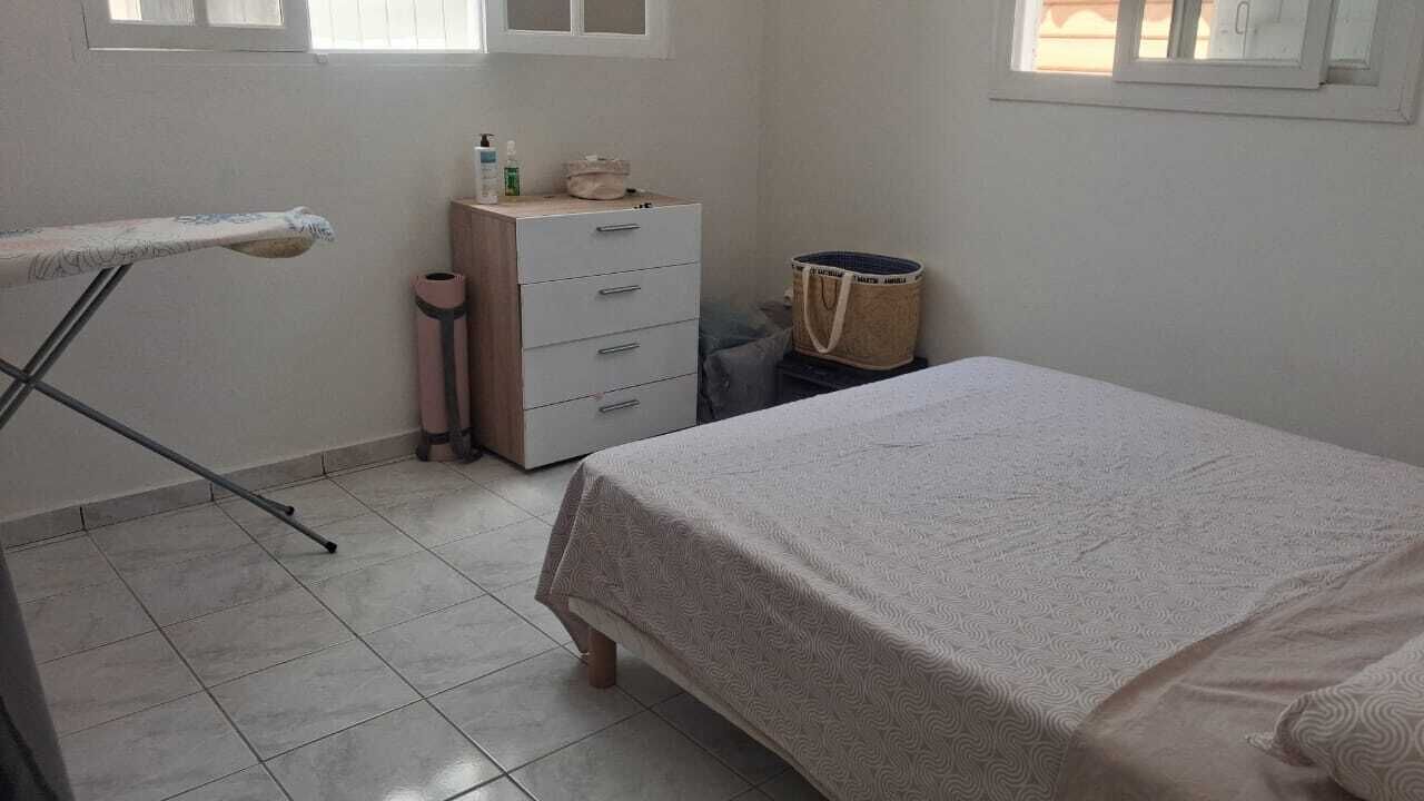 Ein Schlafzimmer mit einem Bett, einem Schminktisch, einem Fenster und einem Wäscheständer.