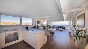 Una cucina moderna con isola centrale, zona pranzo con divano e vista sulla città e sulle montagne.