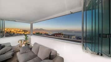 Un soggiorno moderno con un'ampia finestra che si affaccia su una veduta urbana e una montagna.