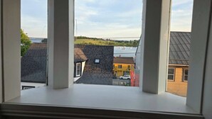 Une baie vitrée donnant sur une ville, avec vue sur des bâtiments et une étendue d’eau.