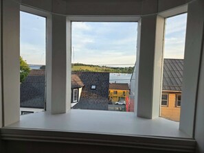 A bay window with a view of a town, including buildings and a body of water.
