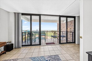 Ein Zimmer mit einer Schiebetür zu einer Terrasse im Freien mit Stühlen und Blick auf die Landschaft.