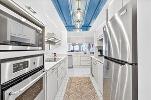 A modern kitchen with stainless steel appliances, white cabinetry, and a patterned tile floor. - Aransas Princess #308, Family-Friendly Gulf-View 2BR/2BA Condo (Port Aransas)