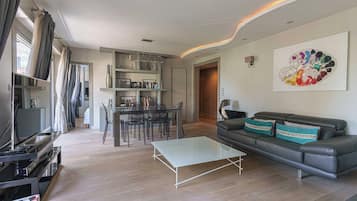 A modern living room with a sofa, coffee table, and a dining area with chairs.