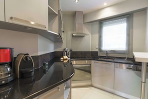 A modern kitchen with stainless steel appliances, a coffee machine, and a window with blinds. - Charming Apartment With Balcony 3br/6p - Deauville (Deauville)