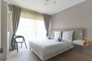 A hotel room with a bed, a chair, a bedside table, and a window with curtains. - Charming Apartment With Balcony 3br/6p - Deauville (Deauville)