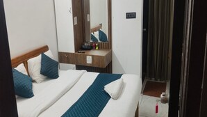 A hotel room with a bed, a wooden headboard, a mirror, a bedside table, and a door. - Collection O Thanisandra Bangalore (Bengaluru)