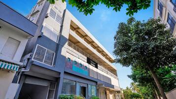 A multi-story building with a ground-level commercial space, a balcony on the second floor, and a clear sky.