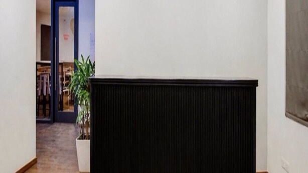 A reception area with a black counter, a hanging pendant light, and a door leading to another room. - Collection O Thanisandra Bangalore (Bengaluru)
