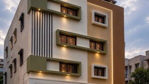 A modern multi-story building with distinct architectural features, including a combination of vertical and horizontal lines, and a mix of window styles. - Collection O Thanisandra Bangalore (Bengaluru)
