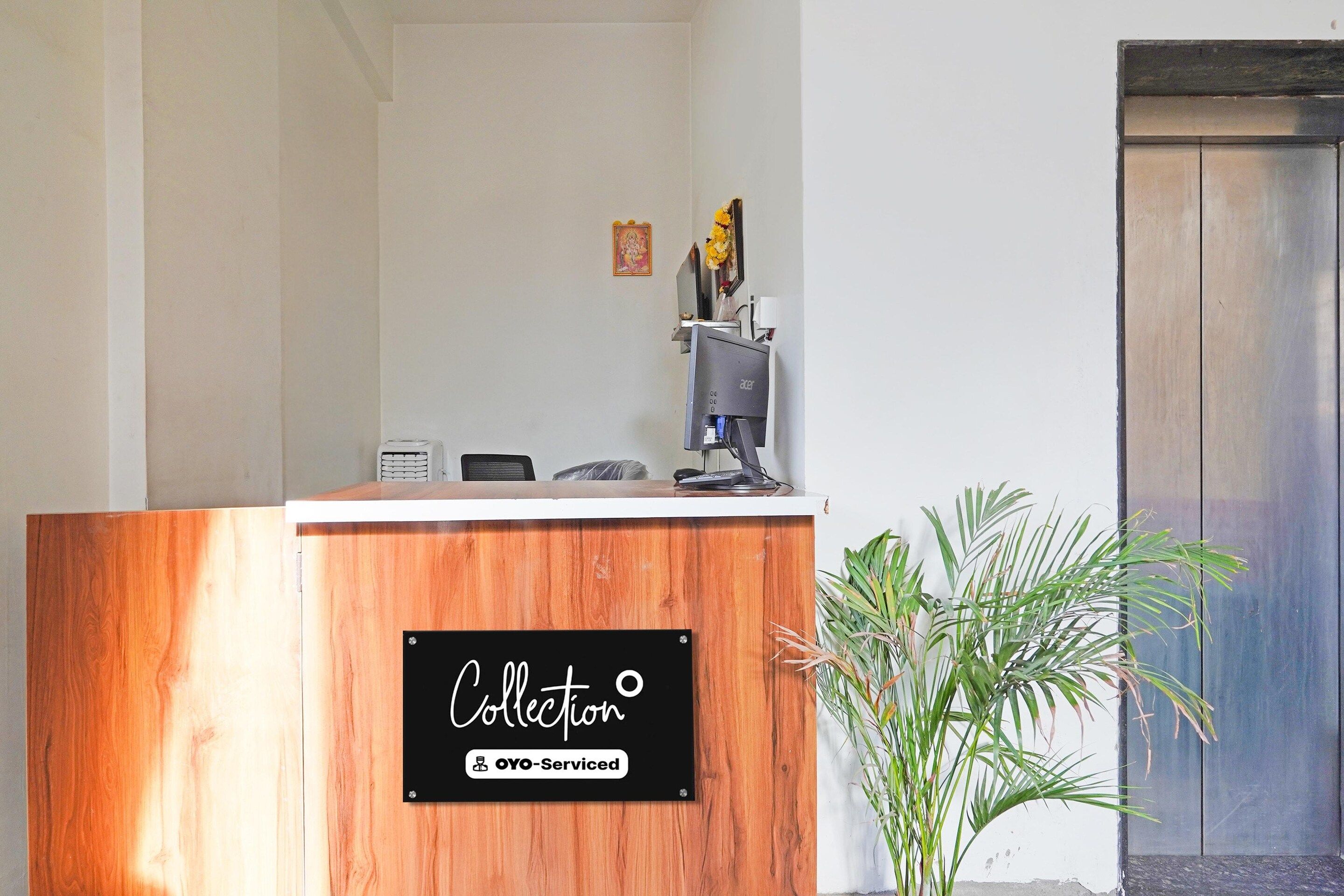 Un comptoir d’accueil avec un revêtement en bois, un ordinateur et une petite plante à côté.