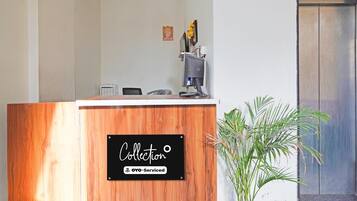 Un comptoir d’accueil avec un revêtement en bois, un ordinateur et une petite plante à côté.