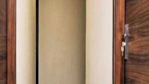 A narrow hallway with wooden doors on either side and a ceiling with recessed lighting. - Collection O Thanisandra Bangalore (Bengaluru)