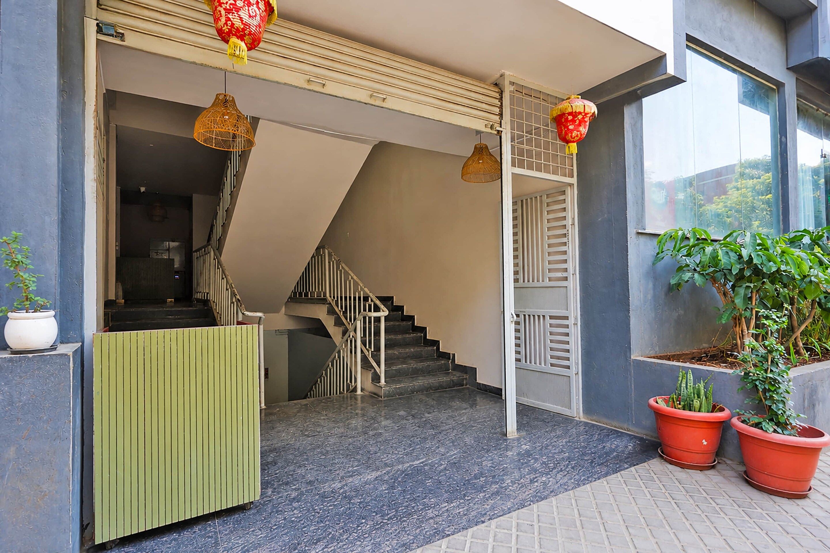 A modern building entrance with a staircase, a reception desk, and potted plants.