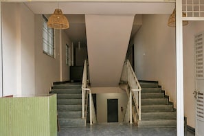 A staircase with a handrail, a door at the bottom, and a hanging light fixture. - Collection O Thanisandra Bangalore (Bengaluru)